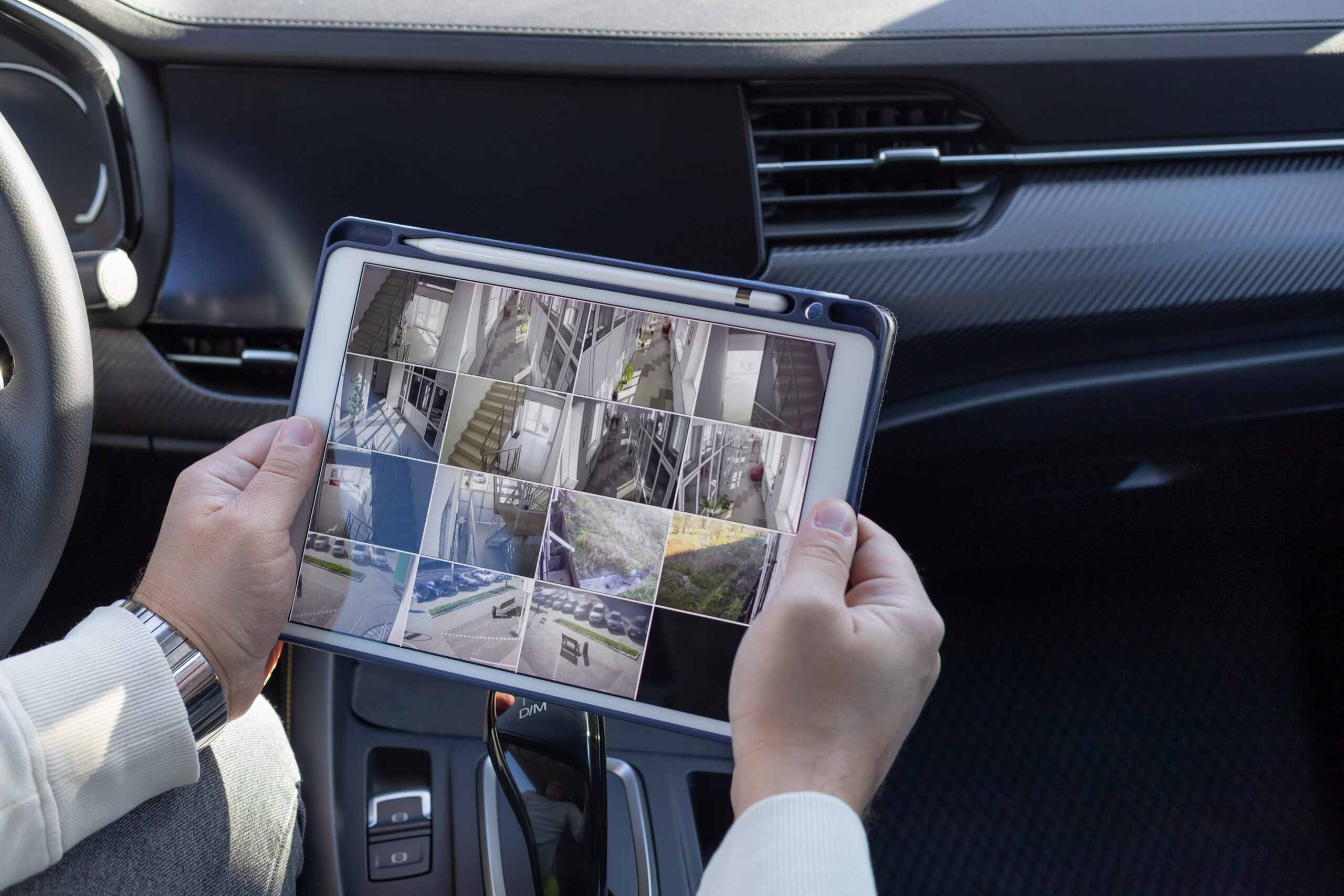 Man monitoring modern cctv cameras on digital tablet sitting in the car. online security system. copy space